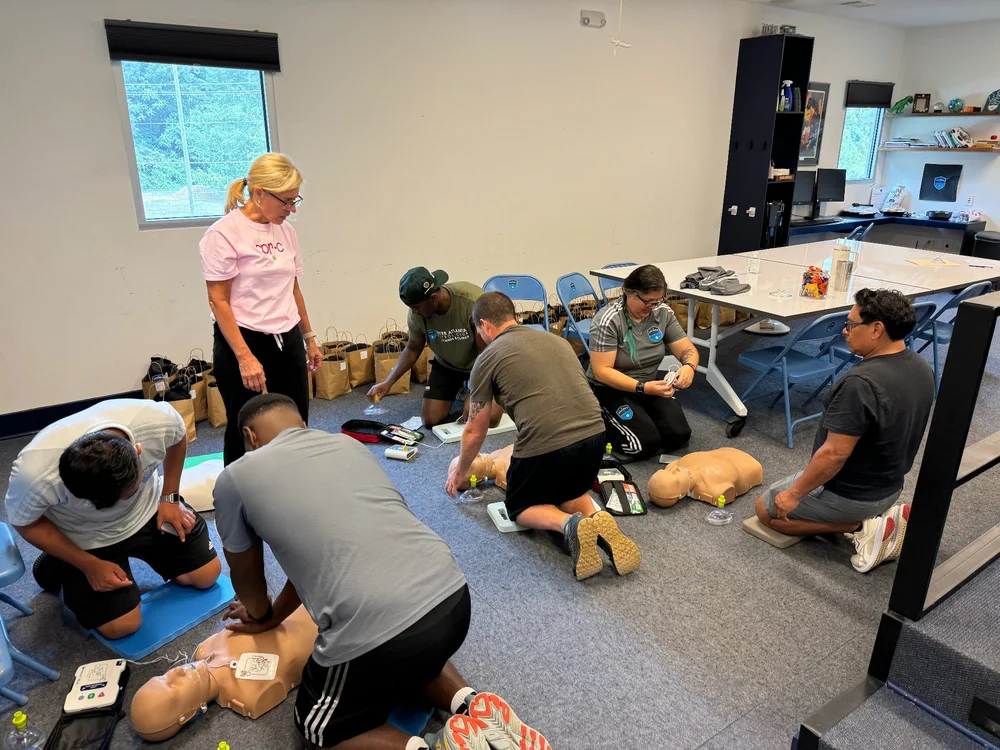 A group practicing CPR on manikins during an on-site training session