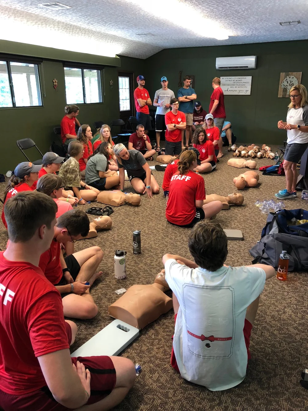 A CPR class seated around manikins as the instructor demonstrates