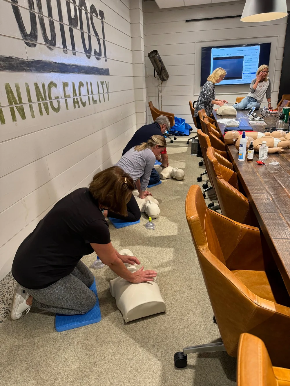 A group practicing CPR on manikins in a conference room